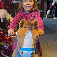 Lya a rejoint le concours — aidez-le/la à gagner de superbes lots ! child, christmas_tree, cute, festive_decorations, floor_tiles, fun, hair_bun, happy, holiday, home_interior, indoor, joy, person, play, plush_toy, red_clothing, smiling, toddler, toy_horse, young_child