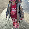 Aaliyah is registered to the contest to win money with this photo: child, girl, heart_shaped_sunglasses, red_bow, silver_jacket, heart_printed_pants, red_shirt, necklace, boots, outdoor, sunlight, pavement, smiling, fashion, accessories, winter_clothing, shadow, standing, cute, happy