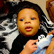 Ka'Marion joined the competition — help win amazing prizes! baby, child, blanket, black_clothing, indoor, person, arm, tattoo, heart_graphics, soft_texture, curly_hair, cute, holding, closeup, portrait, skin, furniture, fabric, comfort, warmth