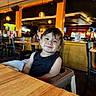 Elijah joined the competition — help win amazing prizes! toddler, child, high_chair, restaurant, smile, black_shirt, wooden_table, indoor, lights, people, furniture, happy, cute, portrait, casual, seated, baby, person, hair, table