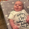 Johnny joined the competition — help win amazing prizes! baby, infant, onesie, clothing, face, person, indoor, changing_pad, pattern, fabric, hand, expression, curious, light_skin, floor, wood_floor, diaper_wipes, package, love_message, casual