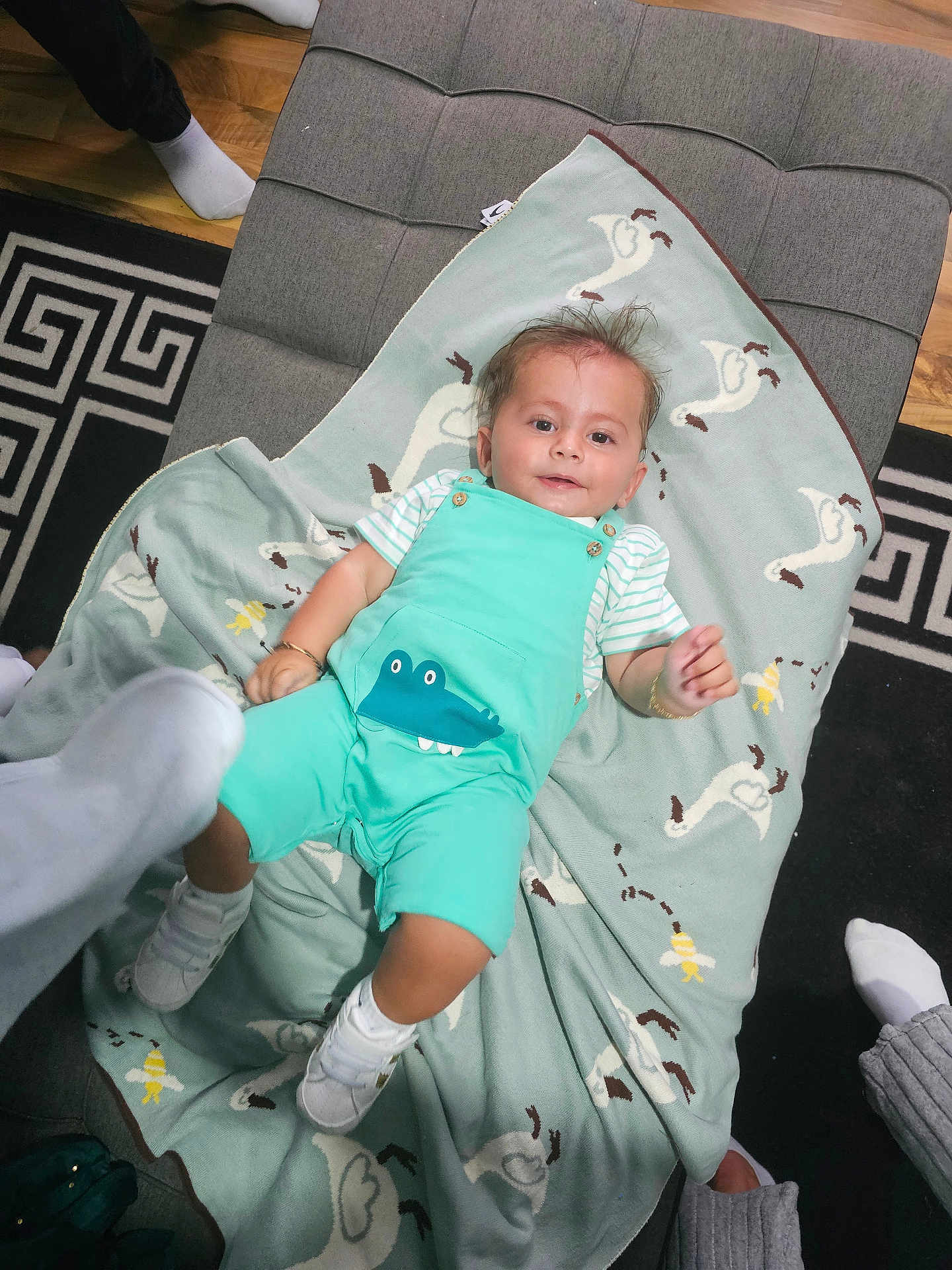 Selym joined the competition — help win amazing prizes! baby, child, blanket, crocodile_print, ottoman, floor, socks, feet, toy, striped_shirt, smile, hair, indoor, wooden_floor, pattern, clothing, person, cute, happy, relaxed