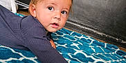 Selym is registered to the contest to win money with this photo: toddler, child, baby, blanket, blue, pattern, indoor, curious, face, expression, long_sleeve, floor, crawling, young, person, skin, hair, hand, portrait, cozy
