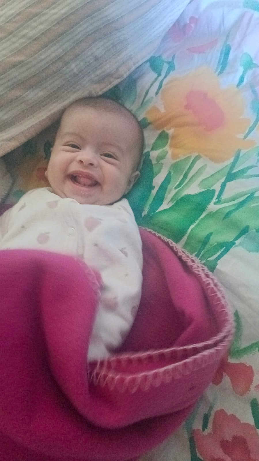 Noursine participe au concours pour gagner de l'argent avec cette photo : baby, bedspread, blanket, child, colorful, cozy, cute, face, floral, happy, head, indoors, infant, lying_down, person, pink, portrait, sleepwear, smiling, wrapped