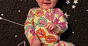 Stella joined the competition — help win amazing prizes! baby, child, smiling, onesie, headband, bow, patterned_clothing, star_pattern, quilt, constellation, black_background, colorful, happy, infant, lying_down, motion_blur, playful, cute, portrait, indoor
