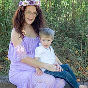 Leo joined the competition — help win amazing prizes! woman, child, outdoor, nature, greenery, floral_crown, lavender_dress, lace, glasses, boy, casual_clothing, jeans, white_shirt, sitting, stone_wall, portrait, family, smile, sunlight, plants