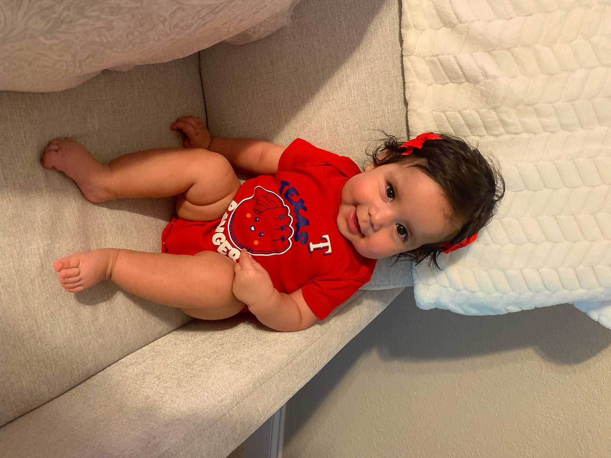 Lucia is registered to the contest to win money with this photo: abdomen, baby, baby_toddler_clothing, child, comfort, face, flooring, foot, happy, human_body, human_leg, joy, knee, leg, person, sitting, smile, sock, thigh, toddler