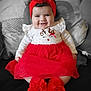 Yasmine a rejoint le concours — aidez-le/la à gagner de superbes lots ! baby, infant, smiling, headband, red_headband, red_dress, tulle_skirt, booties, pillow, cushion, reindeer_applique, polka_dots, sitting, portrait, indoors, cute, chubby_cheeks, black_and_white_background, holiday_outfit, closeup