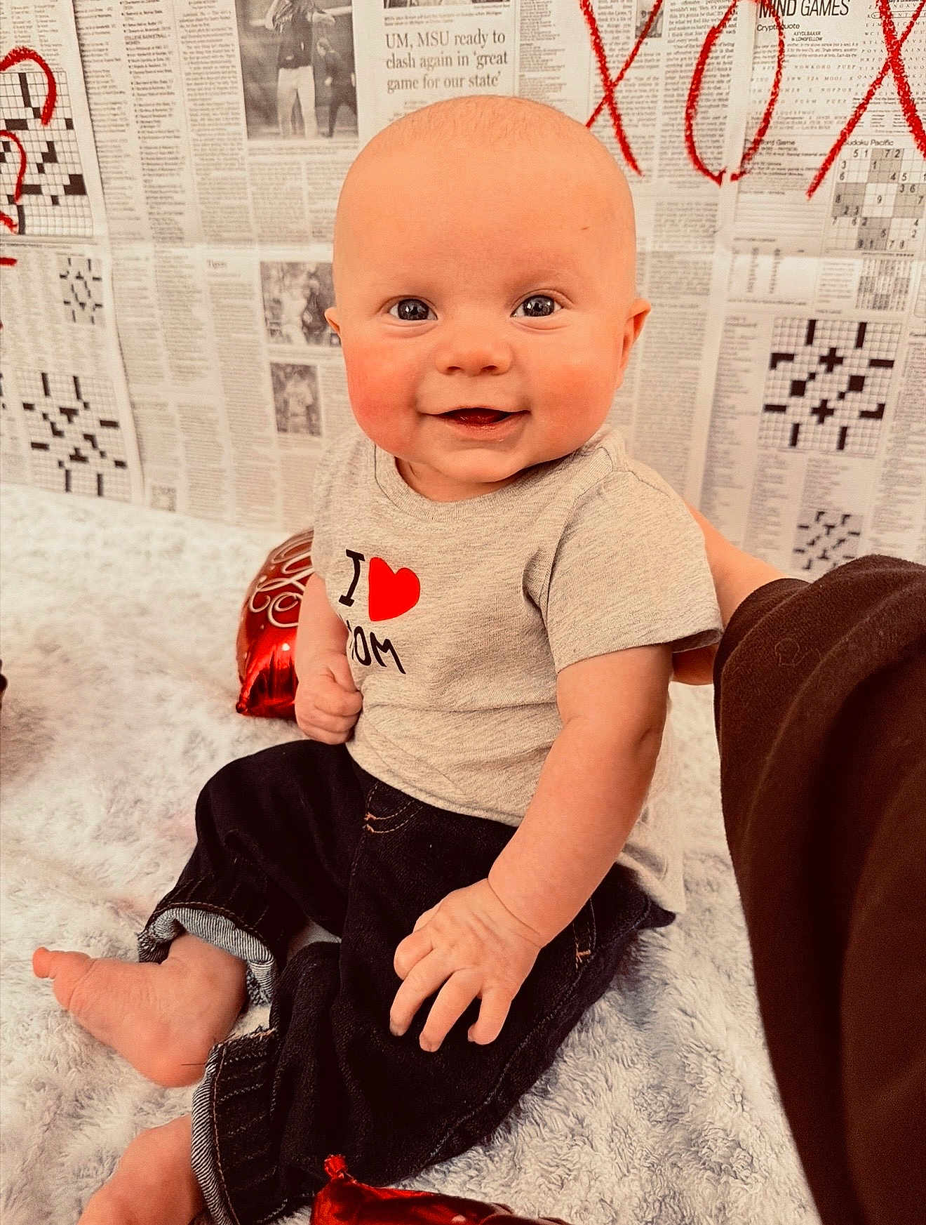 Axel joined the competition — help win amazing prizes! baby, infant, smiling, sitting, onesie, heart_graphic, denim_pants, blanket, newspaper_background, red_balloon, portrait, indoor, cute, chubby_cheeks, bare_foot, hand, big_eyes, gaze, happy, photography