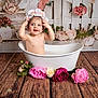 baby, child, bathtub, flower_crown, flowers, wooden_floor, backdrop, studio_shot, smiling, playful, water, tub, floral, pink, portrait, innocence, toddler, cute, sitting, prop