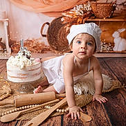 Melya a rejoint le concours — aidez-le/la à gagner de superbes lots ! baby, toddler, child, chef_hat, blue_eyes, cake, frosting, macaron, wooden_spoon, rolling_pin, rug, wood_floor, props, studio_backdrop, bunny_figurine, decor, portrait, crawling, smile, photography