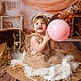 child, baby, toddler, dress, pink_balloon, headband, bow, smile, big_eyes, fur_rug, wood_floor, wicker_basket, dried_flowers, studio_portrait, boho_style, fairy_lights, props, neutral_tones, sitting, portrait