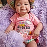 baby, child, smile, hat, pink_clothing, fluffy_blanket, purple_blanket, infant, cute, portrait, happy, indoor, person, sitting, colorful, checkered_pattern, soft_texture, young_child, apparel, relaxed