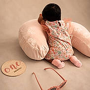Enyla joined the competition — help win amazing prizes! baby, infant, child, floral_outfit, pink_clothing, sitting, back_view, cushion, pillow, plush, indoor, portrait, photoshoot, sunglasses, accessory, one_month, milestone, soft_lighting, pastel_colors, safe