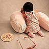baby, infant, child, floral_outfit, pink_clothing, sitting, back_view, cushion, pillow, plush, indoor, portrait, photoshoot, sunglasses, accessory, one_month, milestone, soft_lighting, pastel_colors, safe