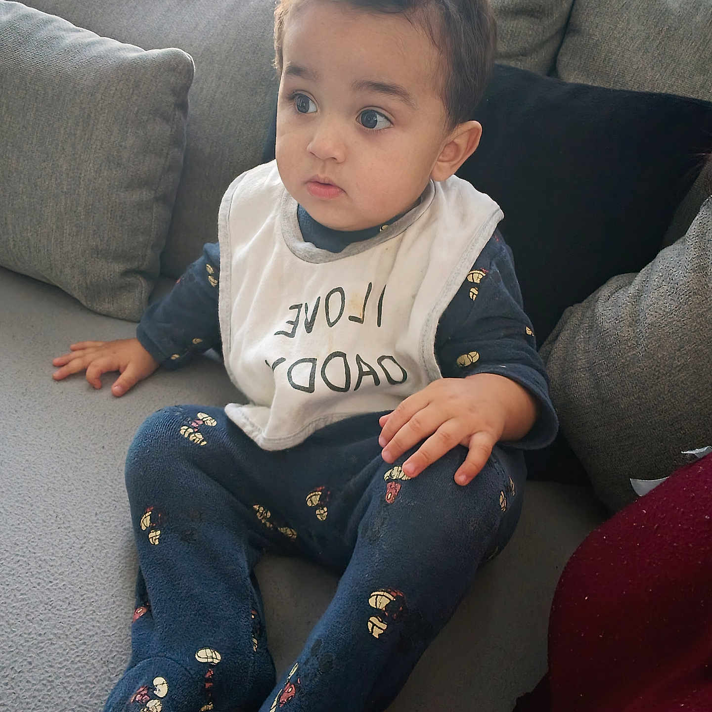 Wassîl participe au concours pour gagner de l'argent avec cette photo : baby, bib, casual, child, clothing, couch, cozy, curious, cute, expression, face, furniture, home, indoor, patterned_clothing, person, portrait, sitting, toddler, young_child