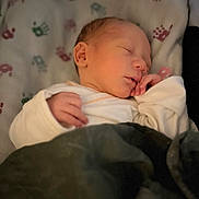 Lamar is registered to the contest to win money with this photo: baby, newborn, sleeping, blanket, bed, cozy, infant, soft_light, hand, face, peaceful, cute, rest, comfort, clothing, indoors, portrait, close_up, child, toddler