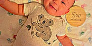 Lamar is registered to the contest to win money with this photo: baby, infant, smiling, onesie, koala, blanket, handprints, wooden_plaque, two_months, cute, lying_down, happy, child, young, portrait, indoors, soft_texture, clothing, person, milestone