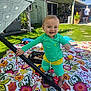 Caysen joined the competition — help win amazing prizes! backyard, barefoot, basket, blanket, casual_clothing, child, colorful, daylight, floral_pattern, grass, green_house, happy, outdoor, person, playtime, pole, smiling, sunny, toddler, toys