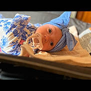 Maylee is registered to the contest to win money with this photo: baby, infant, pacifier, headwrap, blue, floral_onesie, lying_down, blanket, closeup, portrait, big_eyes, cute, indoors, cozy, soft_fabric, newborn, bed, gaze, hand, skin