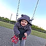 toddler, child, swing, playground, hoodie, smile, outdoor, grass, sky, chain, fence, lamp_post, park, clothing, happy, person, casual, fun, legs, feet