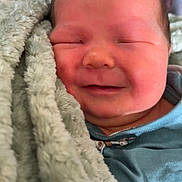 Taytum is registered to the contest to win money with this photo: newborn, baby, smile, blanket, cozy, sleeping, infant, face, child, cute, soft, blue_clothing, animal_print, wrapped, peaceful, indoors, portrait, young_child, warm, snuggled