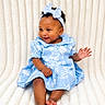 baby, barefoot, blanket, blue_dress, child, curly_hair, cute, earrings, fashion, happy, headband, indoor, infant, patterned_clothing, person, portrait, sitting, smiling, soft_texture, toddler