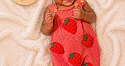 Isla is registered to the contest to win money with this photo: baby, infant, red_bow, strawberry_pattern, romper, blanket, wooden_plaque, smiling, cute, lying_down, portrait, child, happy, headband, skin, feet, hands, button, fabric, texture