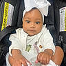 Isla is registered to the contest to win money with this photo: baby, infant, child, car_seat, white_bow, headband, white_clothing, cute, hands, feet, portrait, indoor, seatbelt, smiling, closeup, adorable, skin, face, eyes, person