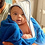 Myles is registered to the contest to win money with this photo: baby, towel, blue_towel, hooded_towel, child, infant, person, hand, beard, face, skin, curious, indoor, portrait, wrapped, newborn, cute, soft_lighting, expression, holding