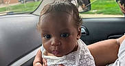 Tajhire joined the competition — help win amazing prizes! baby, child, infant, person, car_interior, car_window, seat, hand, clothing, shorts, shirt, pout, curly_hair, skin, face, window_crack, outside_view, grass, building, parking