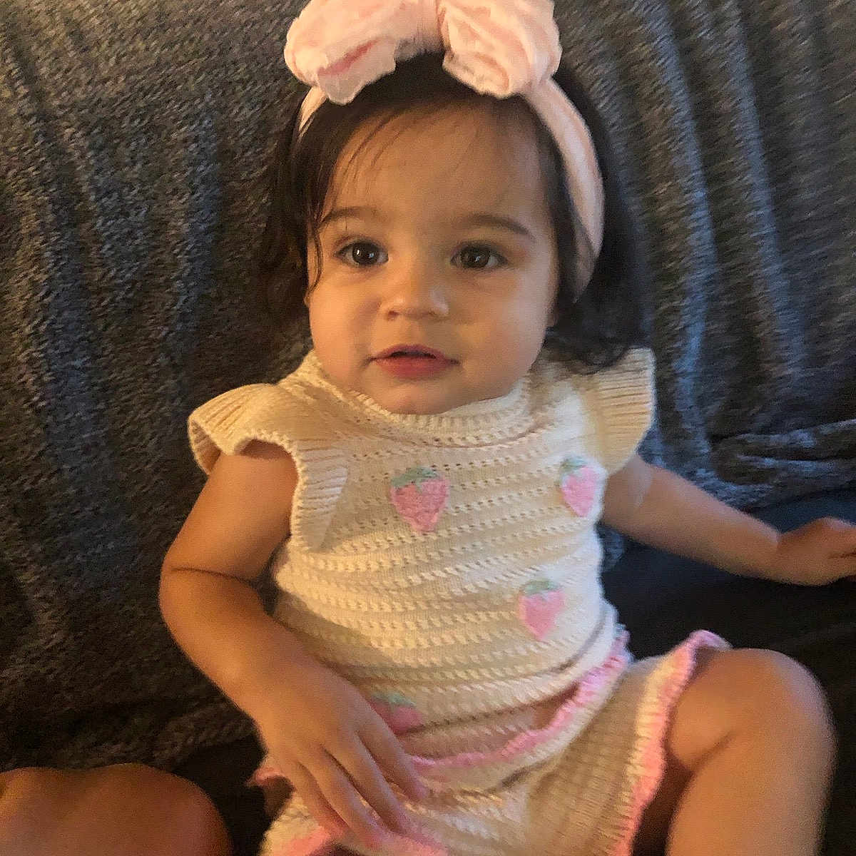 Amaiyah is registered to the contest to win money with this photo: toddler, child, girl, headband, pink, knitted_outfit, strawberry_pattern, couch, indoor, portrait, sitting, curious, cute, soft_lighting, short_sleeve, young_child, person, home, relaxing, casual