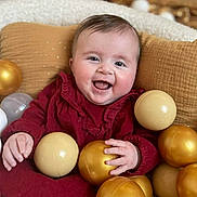 Alix participe au concours pour gagner de l'argent avec cette photo : baby, smiling, child, red_clothing, golden_balls, cream_balls, pillow, blanket, happy, indoors, face, hand, infant, cute, play, sitting, soft_texture, portrait, warm_colors, joyful