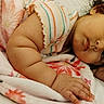 baby, infant, child, curly_hair, lying_down, blanket, floral_blanket, bed, portrait, face, eyes, hands, chubby_cheeks, looking_at_camera, indoor, cozy, sleepwear, striped_clothing, relaxed, photography