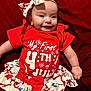 Zara is registered to the contest to win money with this photo: baby, infant, smile, red_clothing, white_skirt, bow_headband, celebration, 4th_of_july, festive, cute, portrait, child, happy, holiday, star_pattern, sitting, person, fabric, clothing, red_background