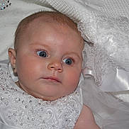 Saoirse is registered to the contest to win money with this photo: baby, infant, face, blue_eyes, white_clothing, lace, beads, blanket, portrait, cute, newborn, soft_texture, closeup, child, adorable, fabric, tulle, earrings, curious, laying_down