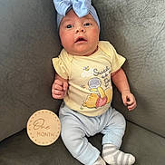 Avery is registered to the contest to win money with this photo: baby, infant, one_month, headband, bow, yellow_onesie, winnie_the_pooh, couch, gray_couch, striped_socks, wooden_milestone, milestone_marker, cute, portrait, seated, indoors, child, smiling, soft_lighting, cozy