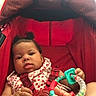 baby, child, closeup, clothing, colorful, curly_hair, cute, expression, foot, hand, indoors, infant, person, playful, red, seatbelt, sitting, stroller, toy, young