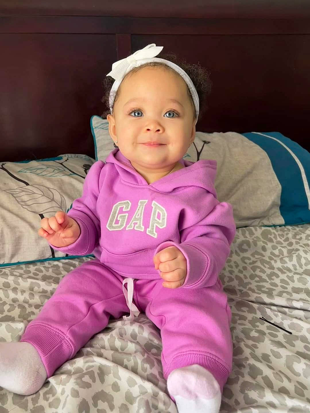 Alani is registered to the contest to win money with this photo: baby, baby_toddler_clothing, cheek, comfort, eye, face, hand, happy, head, human_body, joy, magenta, outerwear, person, pink, purple, skin, sleeve, smile, thumb