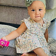 Jovana is registered to the contest to win money with this photo: toddler, child, girl, floral_dress, headband, flower, toy, pink, carpet, rug, couch, indoor, furniture, barefoot, smiling, sitting, cute, playful, young_child, home