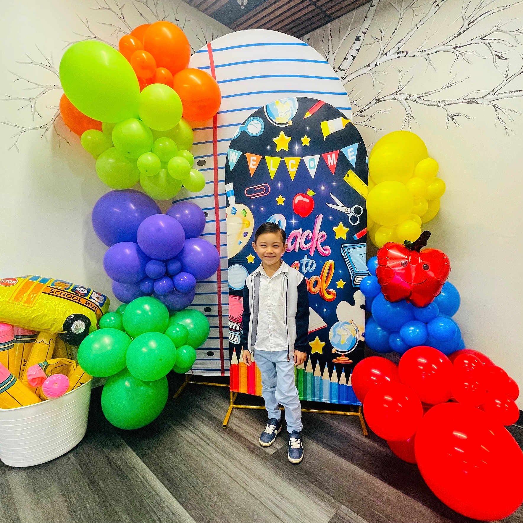 Jovan is registered to the contest to win money with this photo: backdrop, balloons, boy, casual_clothing, celebration, child, colorful, decorations, event, flooring, happy, indoor, party, portrait, school_bus_balloon, school_theme, smiling, standing, wall, young_person