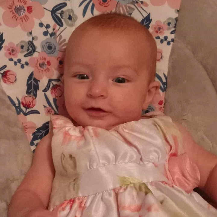 Raven is registered to the contest to win money with this photo: baby, baby_clothes, child, colorful, cushion, cute, eyes, fabric, floral_dress, hand, happy, head, indoor, infant, pattern, person, portrait, skin, smiling, soft