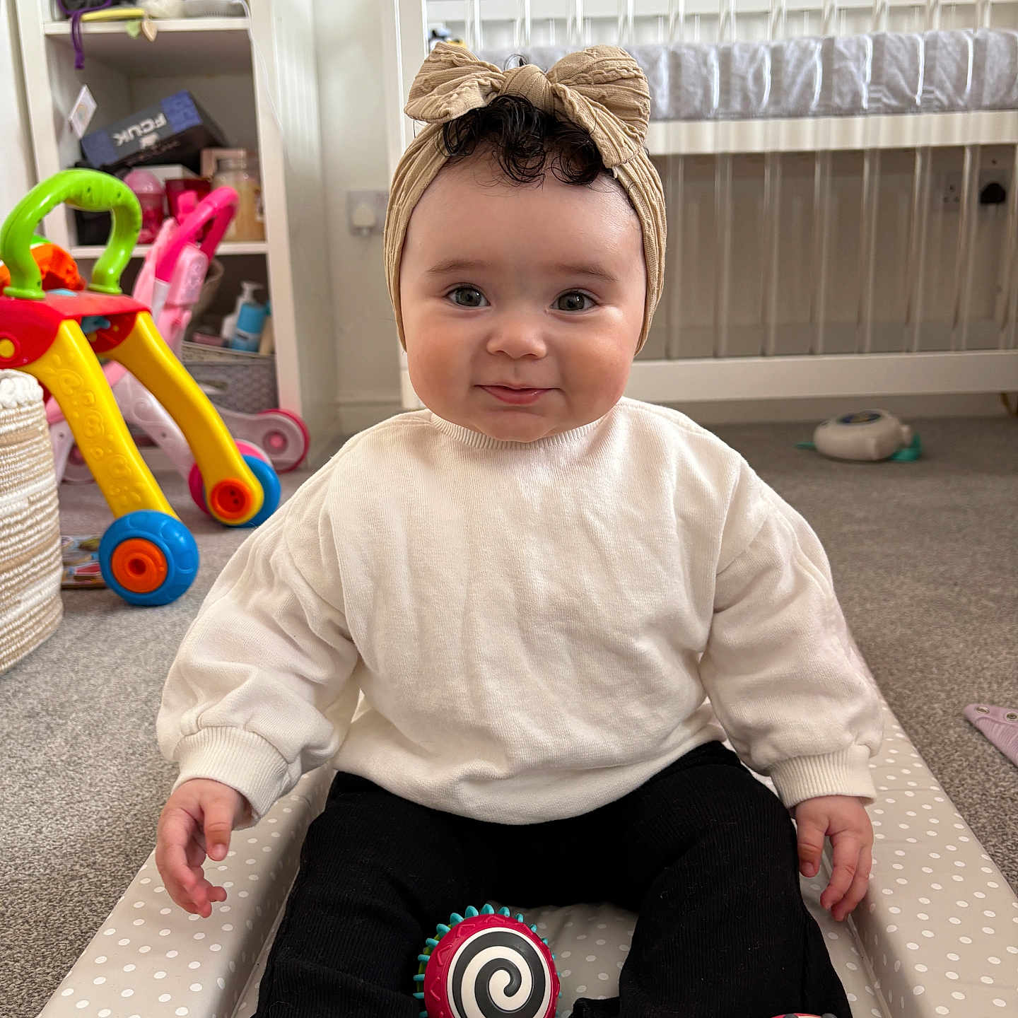 Nova joined the competition — help win amazing prizes! baby, black_pants, carpet, child, cradle, curly_hair, cushion, face, floor, foot, furniture, hand, headwrap, indoor, nursery, play, polka_dot, smile, sweater, toy