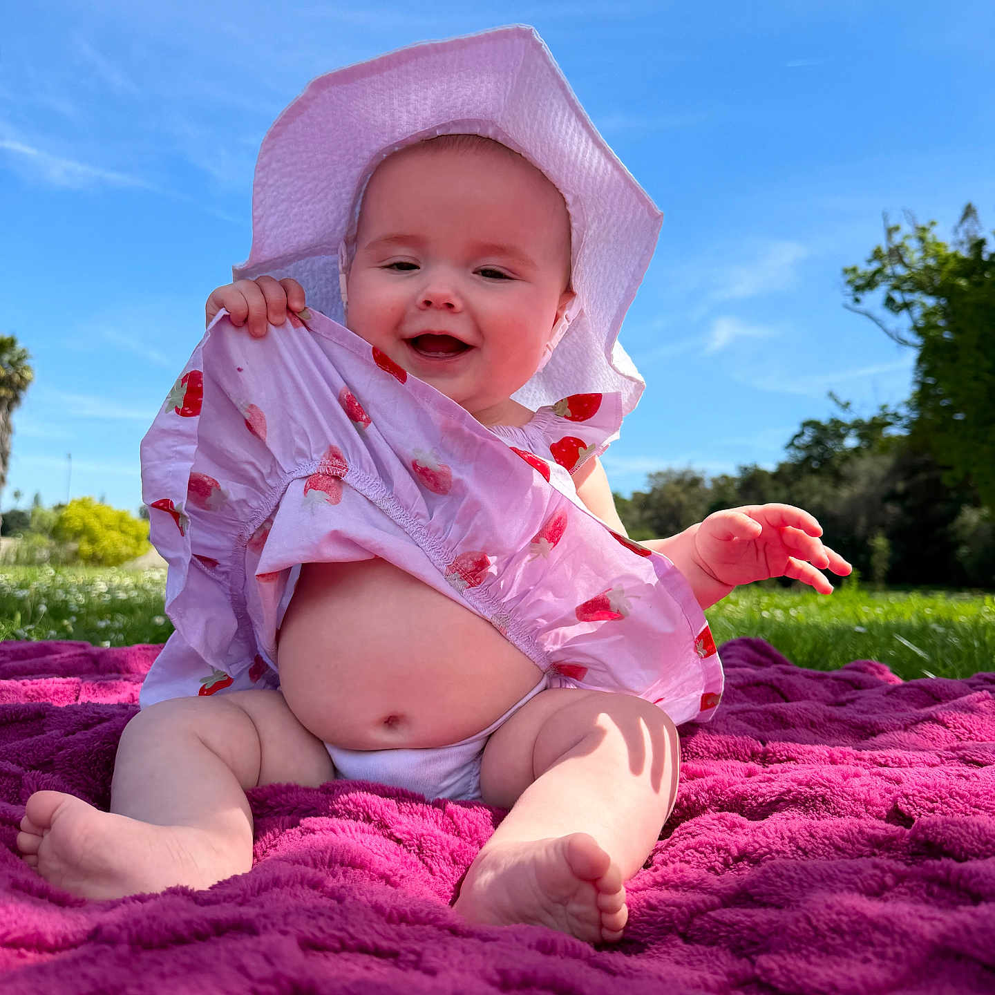 Avery joined the competition — help win amazing prizes! baby, child, smile, hat, dress, blanket, outdoor, grass, sunny, blue_sky, greenery, happy, sitting, infant, playful, nature, cute, summer, barefoot, portrait