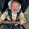 Leyah a rejoint le concours — aidez-le/la à gagner de superbes lots ! baby, child, clothing, cold_weather, face, gold, hair, hand, happy, jacket, outdoor, person, playful, seatbelt, smile, stroller, toddler, transport, urban, wheel