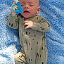Levi joined the competition — help win amazing prizes! baby, infant, pacifier, blanket, blue, onesie, patterned_clothing, outdoor, grass, sleepy, hand, footed_pajamas, newborn, cute, lying_down, soft_texture, sunlight, child, person, relaxed