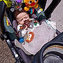 baby, stroller, blanket, toy, sleeping, infant, child, sunlight, outdoor, animal_toy, lion, zebra, pacifier, seat, safety_strap, carrying_handle, colorful, cute, resting, daylight