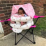 Kenzi is registered to the contest to win money with this photo: baby, infant, blanket, pink, inflatable_seat, camping_chair, outdoor, brick_wall, grass, concrete, foot, hand, child, seat, person, cute, cozy, resting, portrait, toy