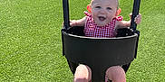 Macie is registered to the contest to win money with this photo: baby, child, swing, playground, green_turf, basketball_hoop, sunlight, happy, smiling, toddler_swing, red_dress, outdoor, park, baby_clothing, person, barefoot, summer, fun, play, joy