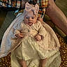 adult_hand, baby, blanket, bow, clothing, cozy, cute, dress, fabric, floor, headband, indoor, infant, legs, lying_down, person, plaid_shirt, skin, soft_texture, wood_floor